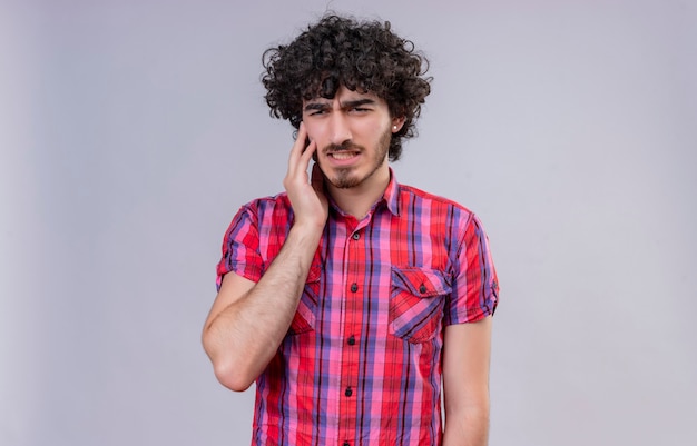 Un hombre guapo triste con el pelo rizado en camisa a cuadros se siente mal