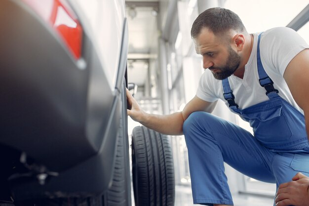 Hombre guapo en uniforme azul comprueba el coche