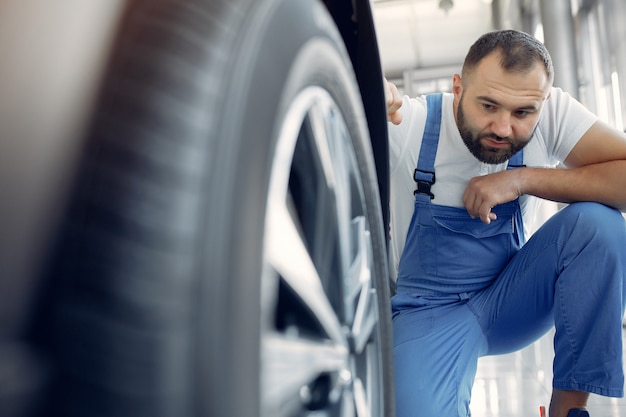 Hombre guapo en uniforme azul comprueba el coche