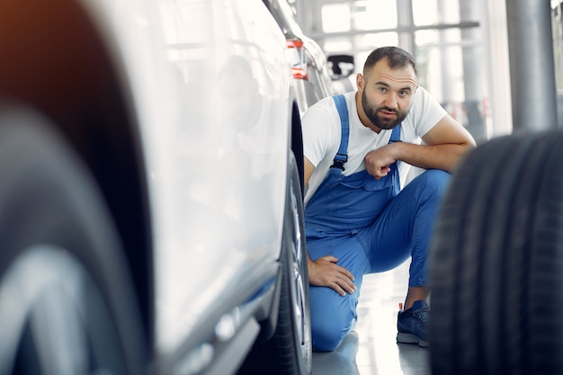 Foto gratuita hombre guapo en uniforme azul comprueba el coche