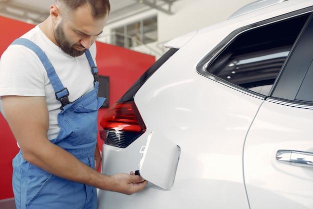 Foto gratuita hombre guapo en uniforme azul comprueba el coche