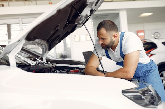 Foto gratuita hombre guapo en uniforme azul comprueba el coche