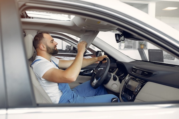 Hombre guapo en uniforme azul comprueba el coche