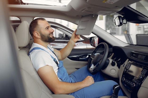 Hombre guapo en uniforme azul comprueba el coche