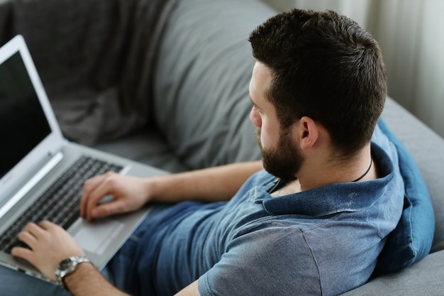 Hombre guapo usando laptop en casa. Concepto de teletrabajo