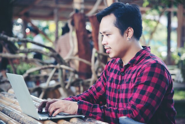 Hombre guapo usando laptop en la naturaleza de viaje