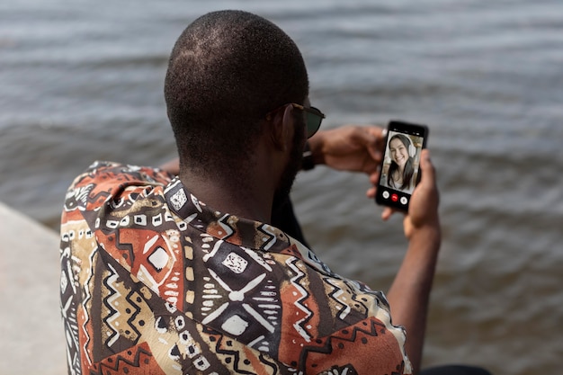 Hombre guapo con una videollamada con smartphone moderno al aire libre