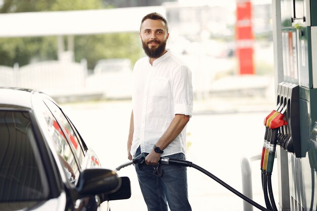 Hombre guapo vierte gasolina en el tanque del automóvil