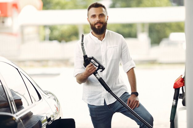 Hombre guapo vierte gasolina en el tanque del automóvil