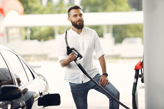 Hombre guapo vierte gasolina en el tanque del automóvil