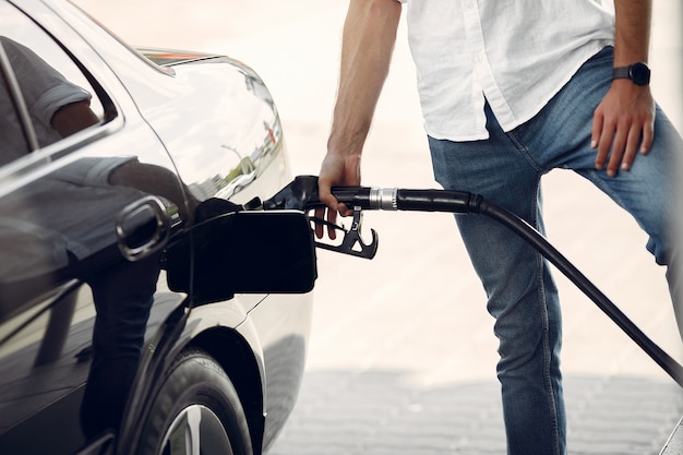 Hombre guapo vierte gasolina en el tanque del automóvil