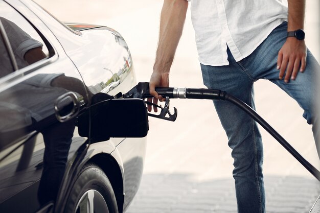 Hombre guapo vierte gasolina en el tanque del automóvil