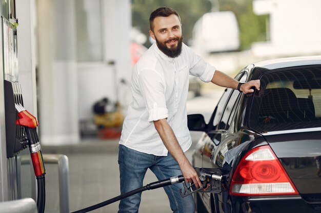 Hombre guapo vierte gasolina en el tanque del automóvil