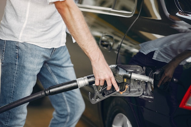 Hombre guapo vierte gasolina en el tanque del automóvil