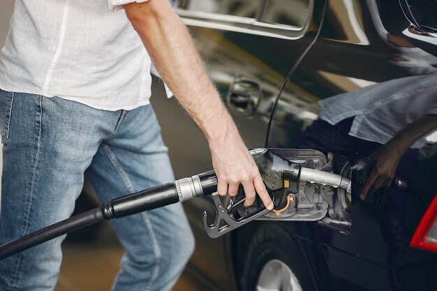 Hombre guapo vierte gasolina en el tanque del automóvil