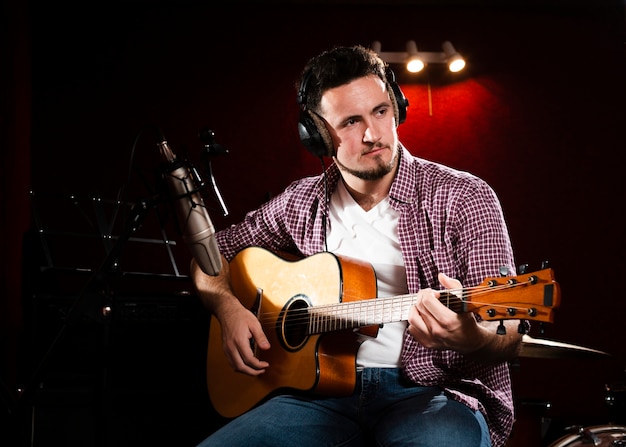 Foto gratuita hombre con guitarra acústica mirando a otro lado