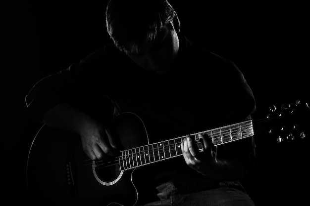 Hombre con guitarra en la oscuridad