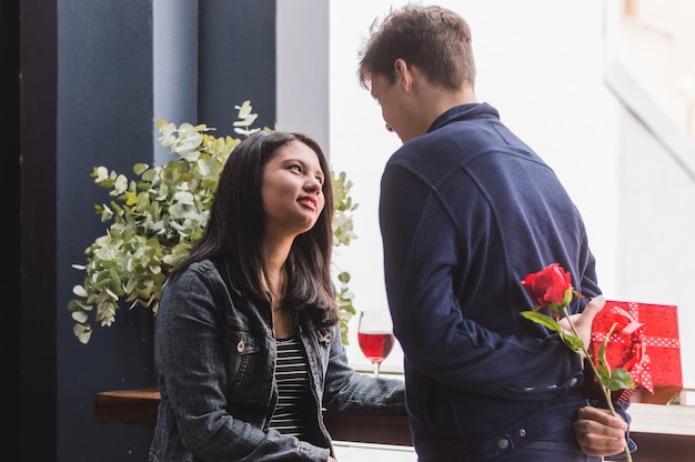 Foto gratuita hombre hablando con su novia y escondiendo en su espalda un regalo y una rosa