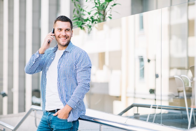 Hombre hablando por teléfono cerca de la valla de vidrio