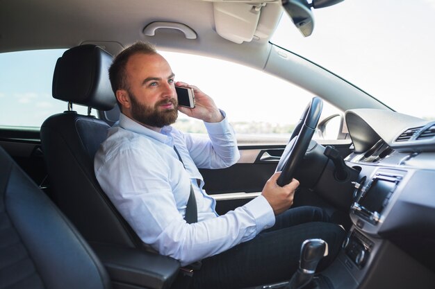 Hombre hablando por teléfono inteligente mientras conduce el coche