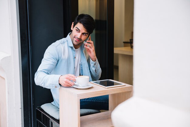 Hombre hablando por teléfono inteligente sentado en el café