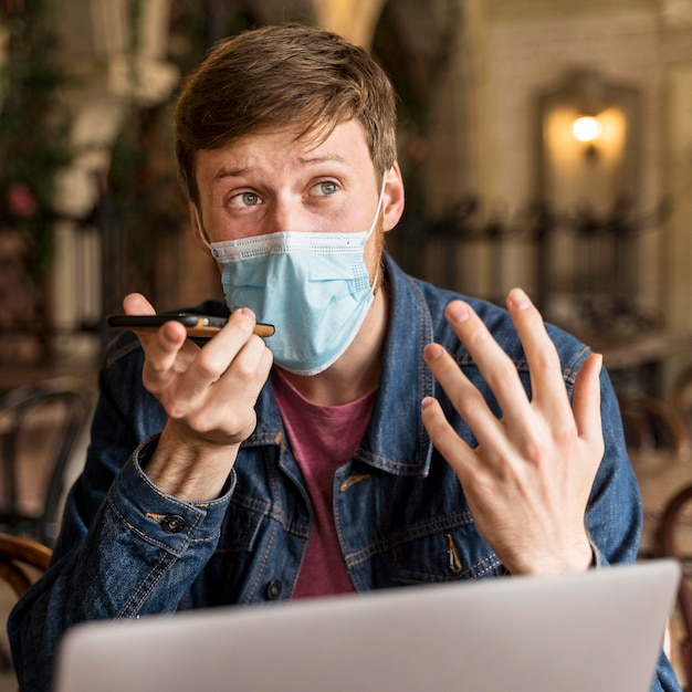 Hombre hablando por teléfono en el interior mientras usa una máscara médica