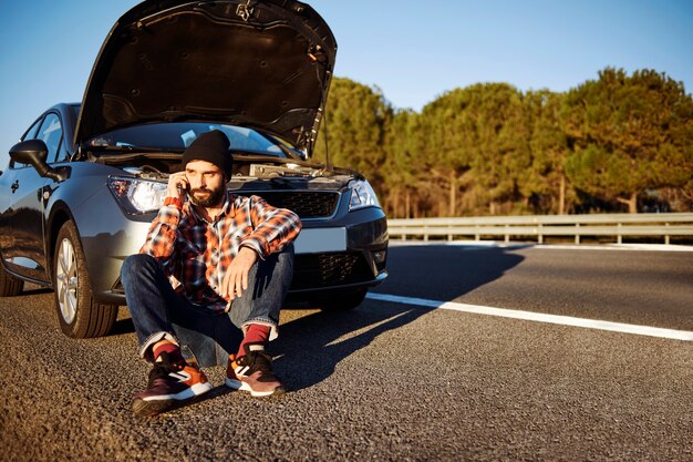 Hombre hablando por teléfono junto al coche