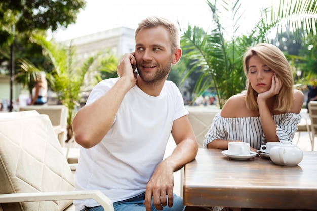 Hombre hablando por teléfono mientras su novia se aburre.