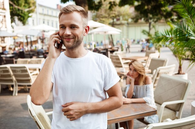 Hombre hablando por teléfono mientras su novia se aburre.