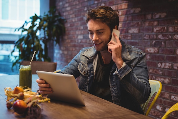 Hombre hablando por teléfono móvil mientras usa tableta digital