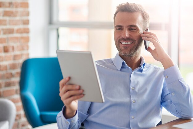 Hombre hablando por teléfono y navegación tableta digital