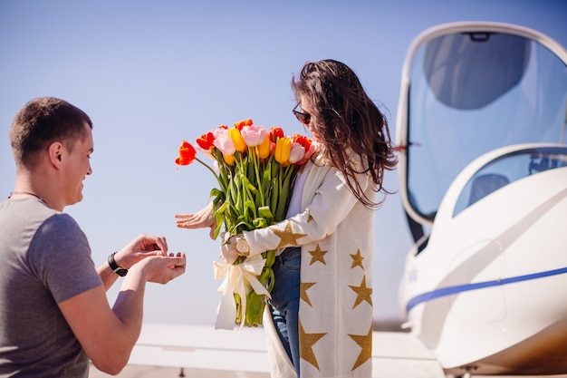 El hombre hace una propuesta a una mujer parada antes de un avión