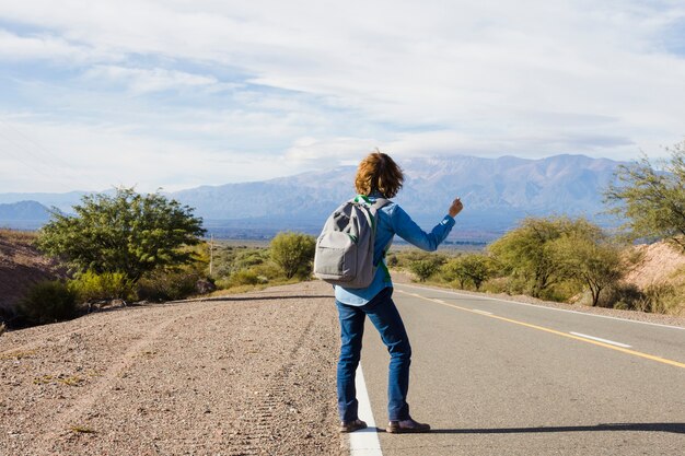 Hombre haciendo autostop al lado de la carretera.