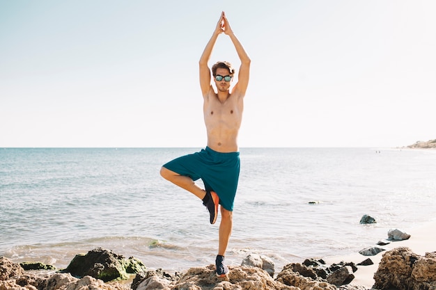 Foto gratuita hombre haciendo ejercicio de equilibrio en la playa