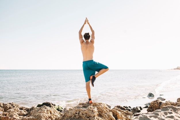 Hombre haciendo ejercicio de equilibrio en la playa