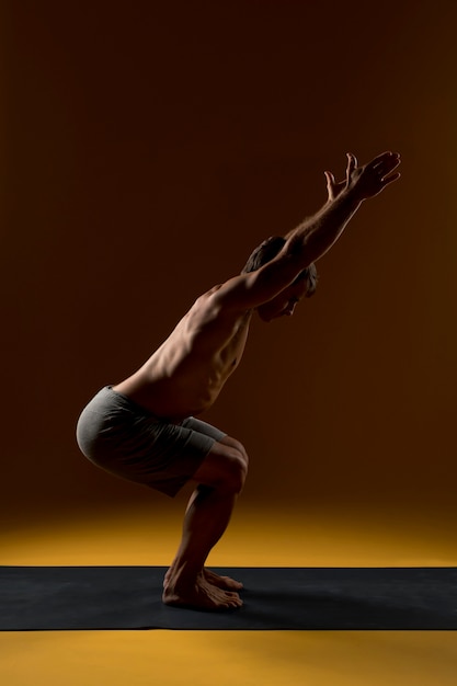 Foto gratuita hombre haciendo ejercicio en estera de yoga