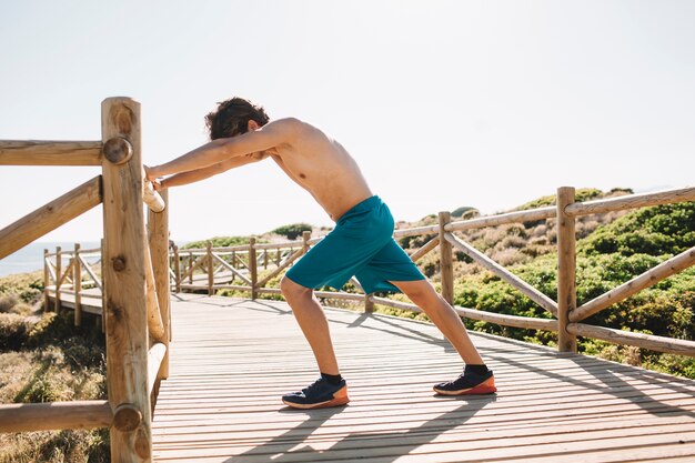 Hombre haciendo ejercicio de estiramiento en la playa