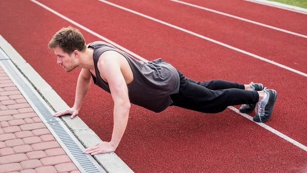 Hombre haciendo ejercicio de flexiones en la pista de carreras