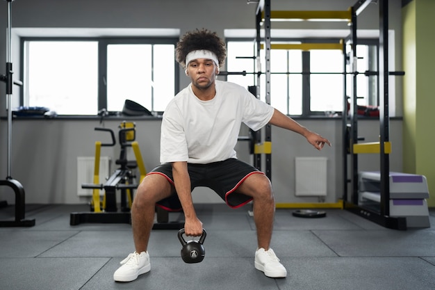 Hombre haciendo ejercicio con pesas rusas en el gimnasio tiro completo