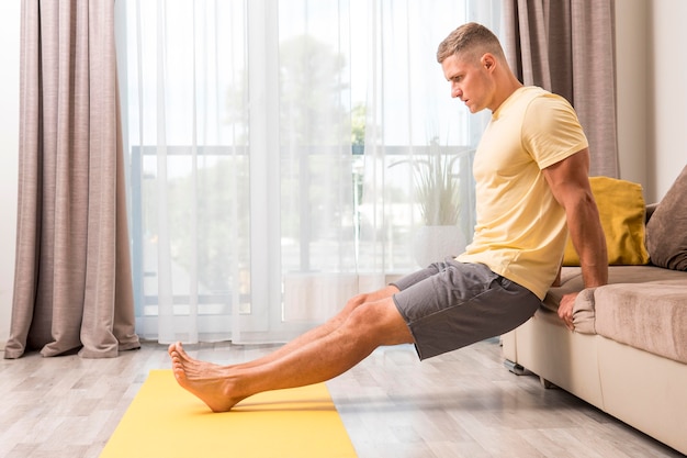 Hombre haciendo fitness en casa con sofá