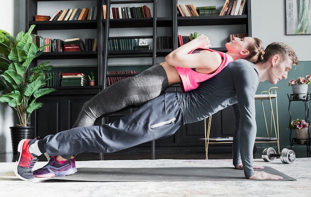 Foto gratuita hombre haciendo flexiones con mujer en la columna vertebral