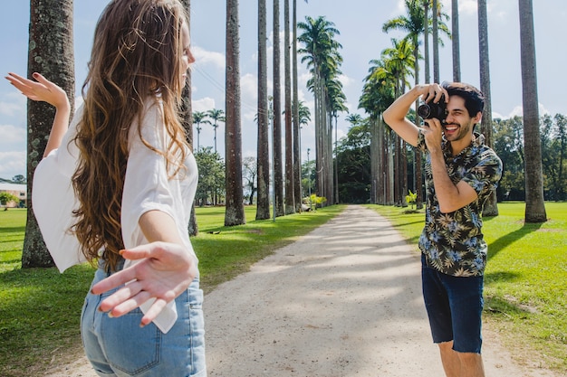 Hombre haciendo foto de chica en camino de palmeras