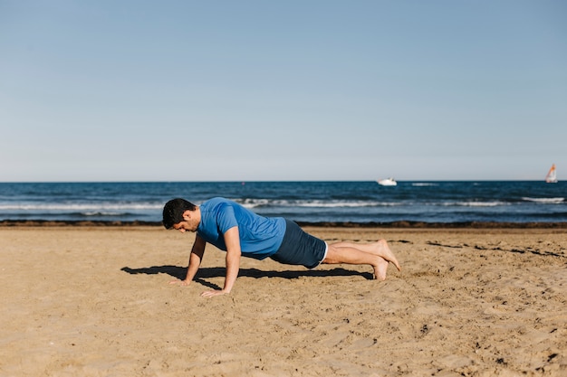 Foto gratuita hombre haciendo lagartijas en la playa