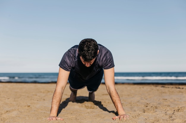 Foto gratuita hombre haciendo lagartijas en la playa