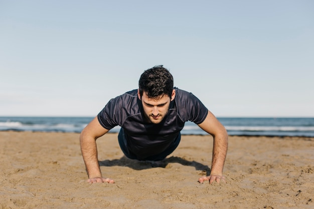 Hombre haciendo lagartijas en la playa