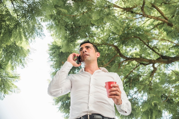 Hombre haciendo llamada debajo de un árbol