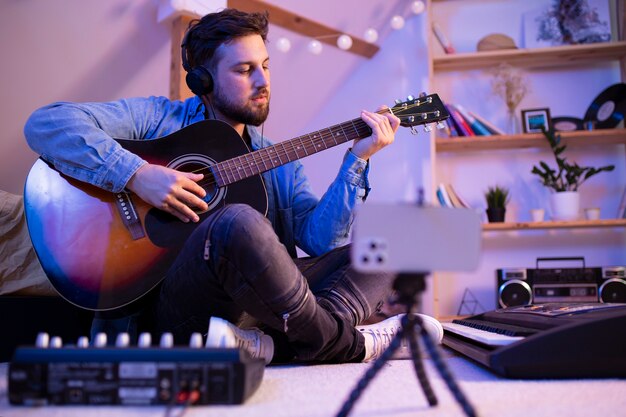 Hombre haciendo música en casa plano completo