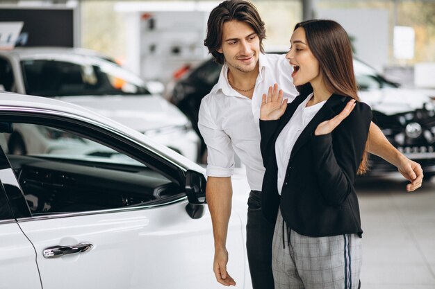 Hombre haciendo un regalo para su mujer en una sala de exposición de automóviles