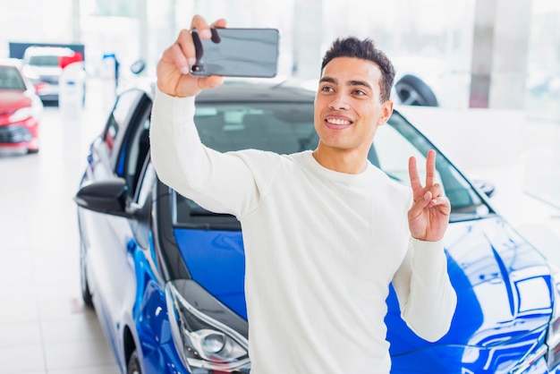 Foto gratuita hombre haciendo selfie en concesionario de coches