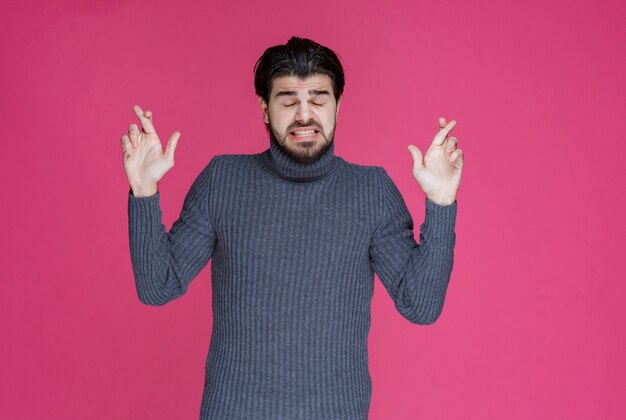 Hombre haciendo signo de cruz de dedo.